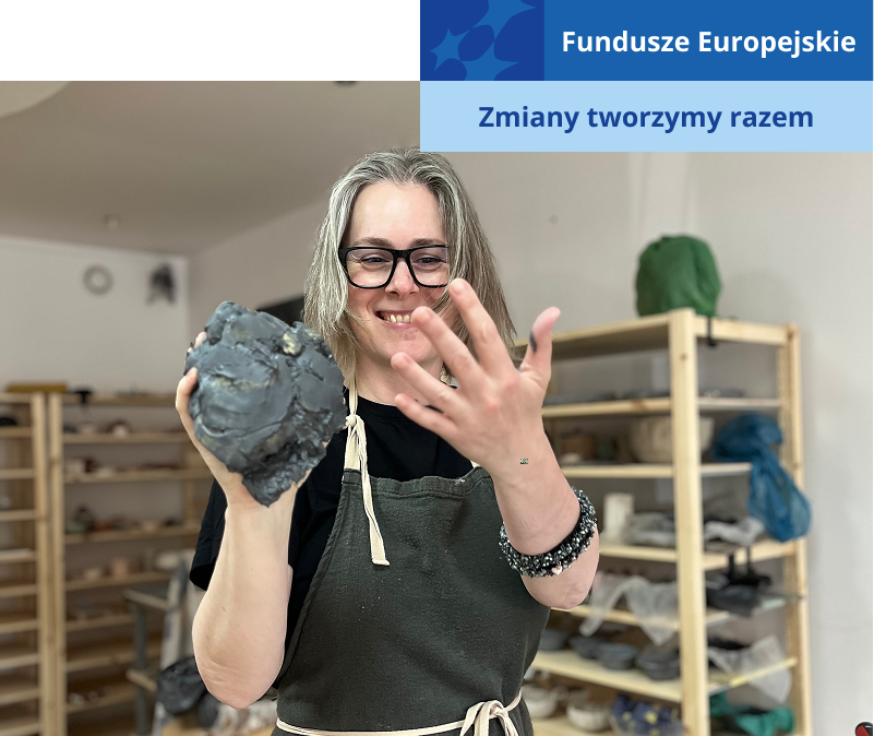 Fotografia przedstawia uśmiechniętą kobietę o jasnych włosach, która urabia glinę. Na sobie ma szary fartuch. Zdjęcie pochodzi z archiwum Ubabrane.