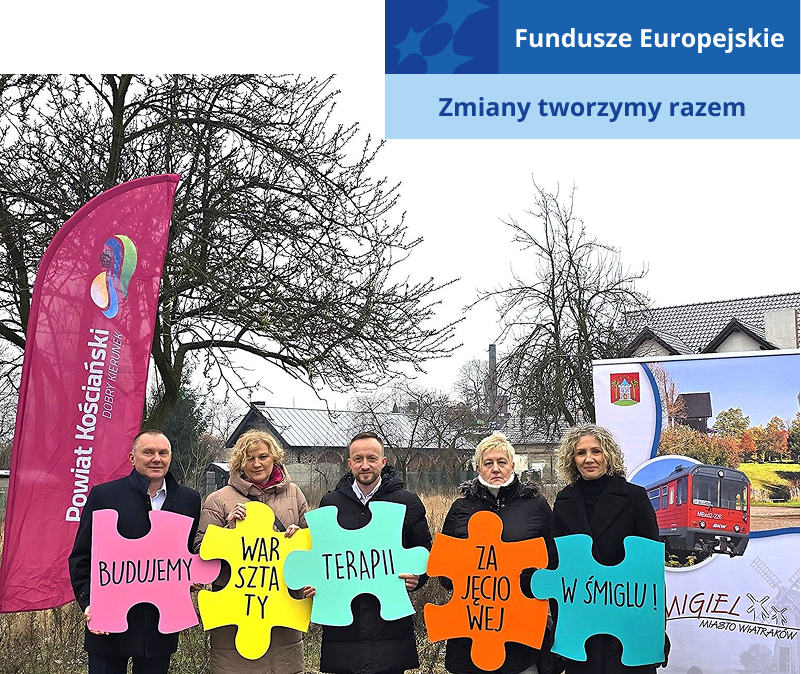 Na ilustracji widocznych jest pięć dorosłych osób, stojących obok siebie, na świeżym powietrzu. Każda z nich trzyma jeden kolorowy puzzel, z wyrazem. Napis układa się w całość: Budujemy warsztaty terapii zajęciowej w Śmiglu.