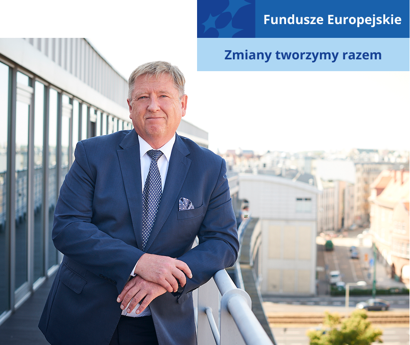 Na zdjęciu znajduje się starszy mężczyzna w garniturze oparty o balustradę na tarasie wysokiego budynku. Fotografia pochodzi z archiwum Wielkopolskiego Funduszu Rozwoju.