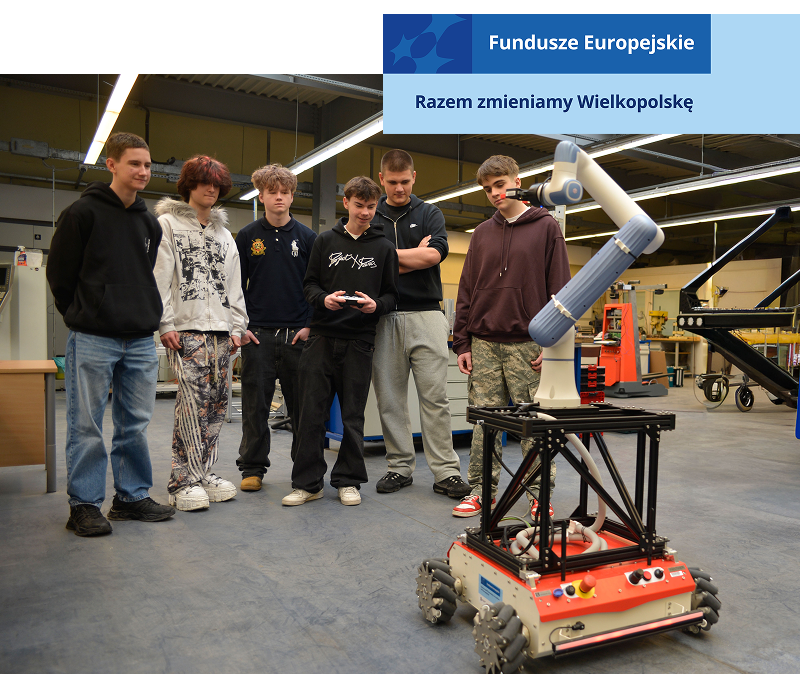 Zdjęcie wykonano w laboratorium maszyn inteligentnych. Sześciu chłopaków przygląda się zdalnie sterowanemu robotowi. Jeden z nich trzyma kontroler. Z prawej strony widoczny jest plakat z napisem Wielkopolska, na niebieskim tle. Autorem fotografii jest Dominik Wójcik.