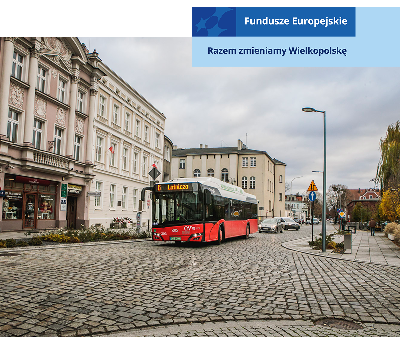 Fotografia przedstawia autobus utrzymany w czerwonych barwach, jadący przez centrum miasta. Zdjęcie pochodzi z archiwum beneficjenta.