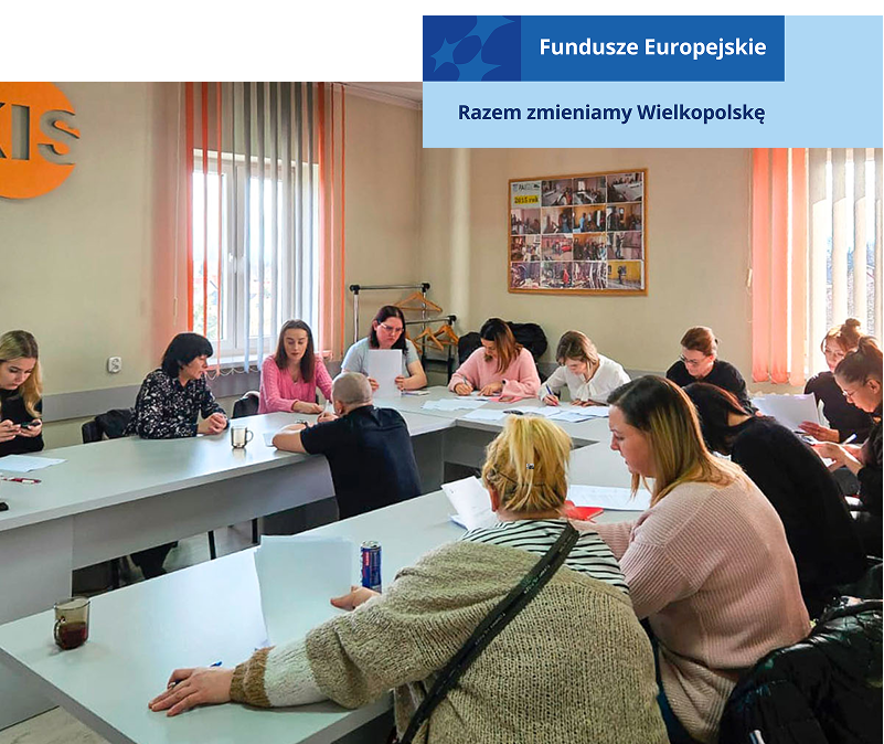 Zdjęcie wykonano w trakcie kursu dla kobiet. Panie siedzą przy stole w kształcie podkowy. W środku znajduje się mężczyzna – prowadzący zajęcia. Fotografia pochodzi z archiwum beneficjenta.