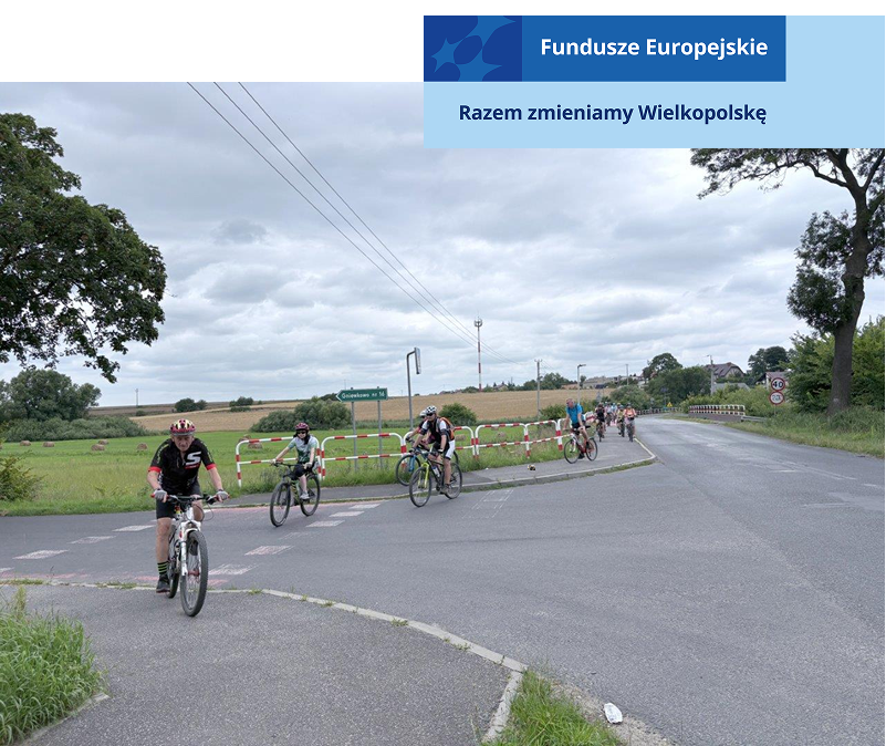 Na zdjęciu widoczni są rowerzyści poruszający się ścieżką rowerową, przecinający drogę. Fotografia pochodzi z archiwum beneficjenta.