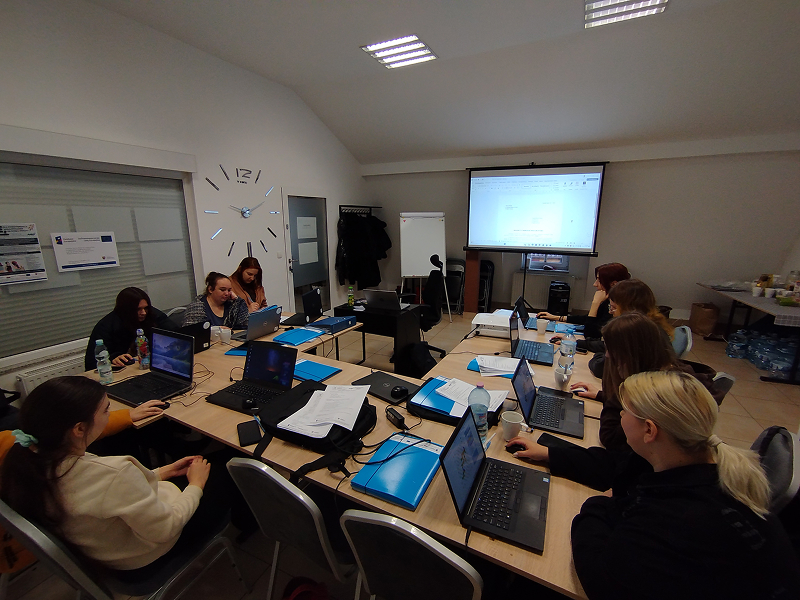 Zdjęcie wykonano podczas kursu komputerowego. Przy stanowiskach komputerowych siedzi kilka kobiet. Fotografia pochodzi z archiwum beneficjenta.