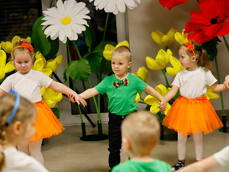 Fotografia przedstawia małe dzieci, ubrane w kolorowe stroje, trzymające się za ręce i tańczące w kole. Zdjęcie pochodzi z archiwum beneficjenta.