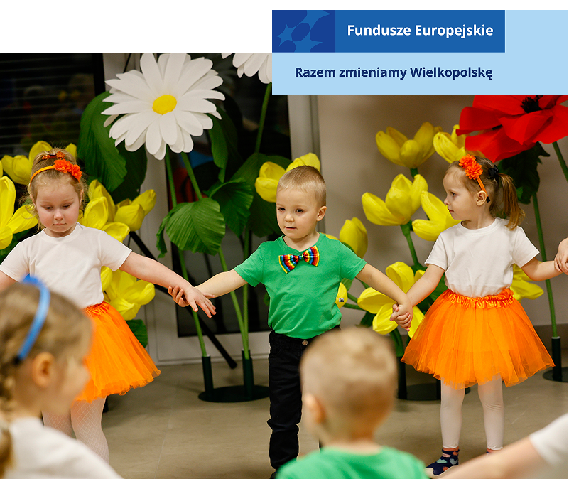 Fotografia przedstawia małe dzieci, ubrane w kolorowe stroje, trzymające się za ręce i tańczące w kole. Zdjęcie pochodzi z archiwum beneficjenta.