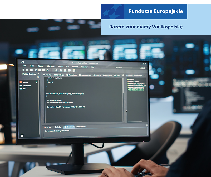 Zdjęcie przedstawia wnętrze centrum komputerowego. Na pierwszym planie widoczny jest monitor z wpisanymi komendami na czarnym ekranie, obsługiwany przez mężczyznę. W tle, rozmazane, widać kolejne monitory. Fotografia pochodzi z adobe stock.