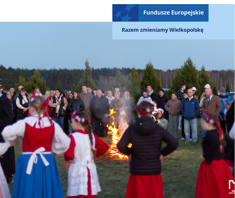 Fotografię wykonano na łące. Spora grupa ludzi, z których część jest w tradycyjnych, ludowych strojach, zgromadziła się wokół ogniska. Zdjęcie pochodzi z archiwum Muzeum Ziemi Rawickiej.