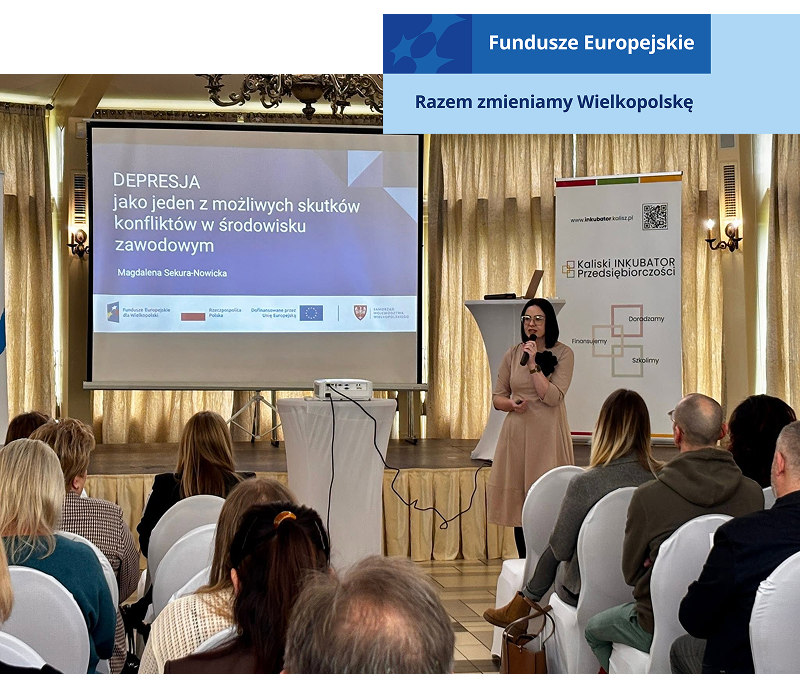 Zdjęcie wykonano w trakcie konferencji. Na scenie stoi kobieta, która przemawia do mikrofonu. Słucha jej licznie zebrana, siedząca publiczność. Fotografia pochodzi z archiwum beneficjenta.