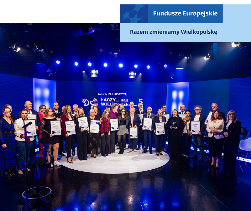 Na zdjęciu znajduje się grupa kilkudziesięciu osób, elegancko ubranych, które stoją na scenie i pozują do wspólnej fotografii. Scena ma miejsce w studio telewizyjnym, widoczne są więc niebieskie ekrany, kamery i oświetlenie. Zdjęcie pochodzi z archiwum Urzędu Marszałkowskiego Województwa Wielkopolskiego.