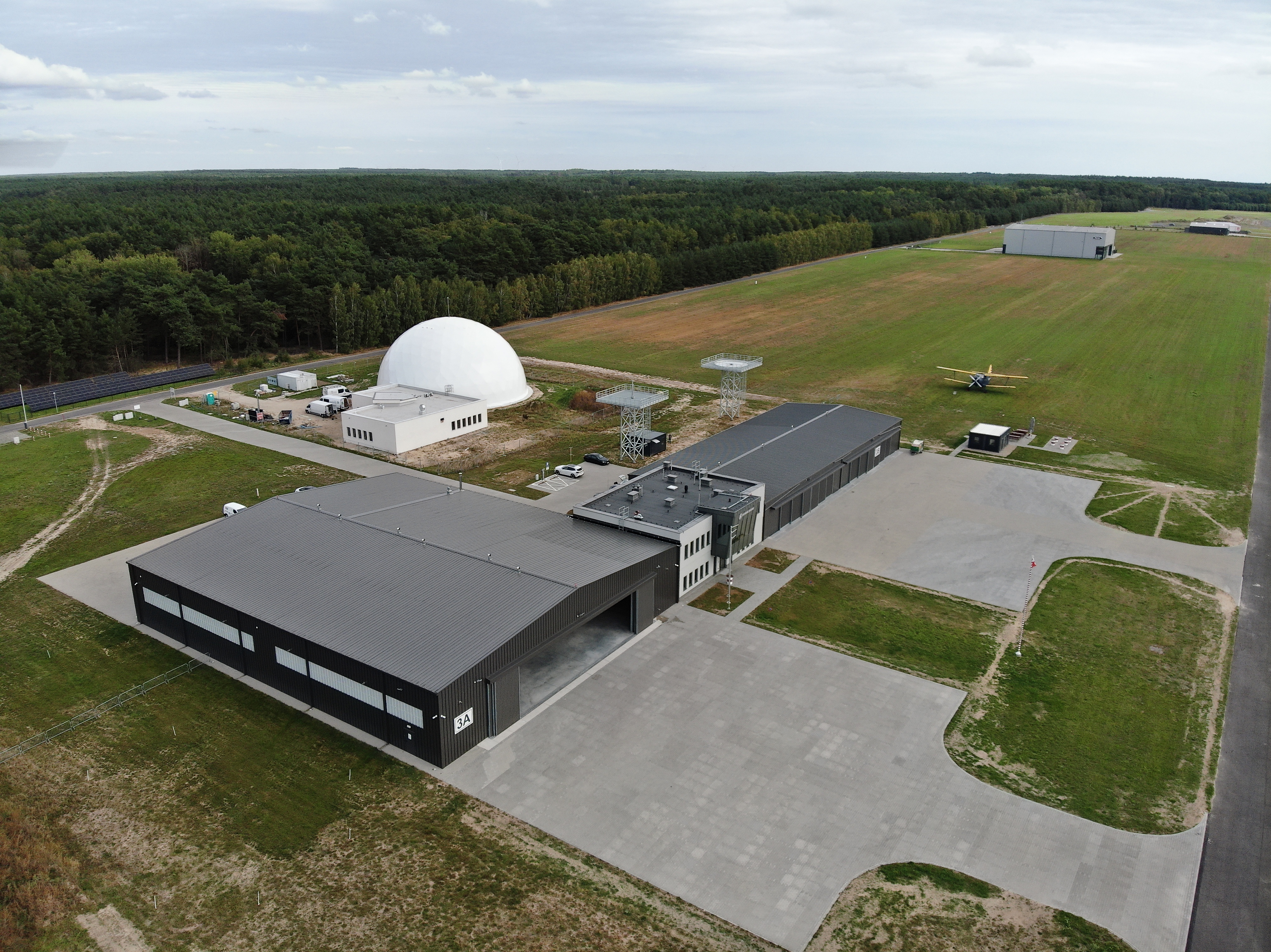 Na zdjęciu widać z lotu ptaka duże lotnisko z dwoma budynkami 