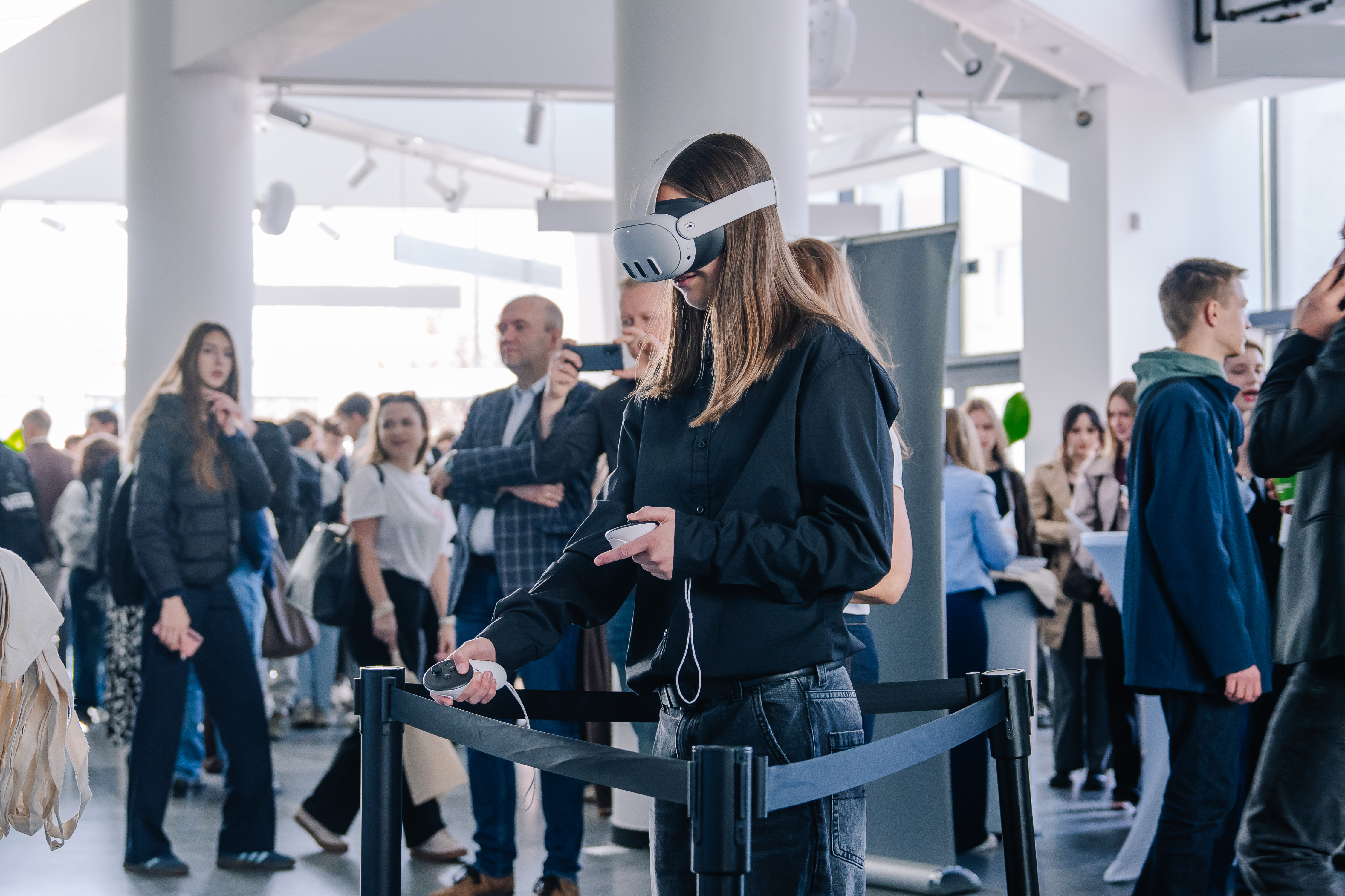 Na zdjęciu kilkanaście osób, jedna z nich ma założone gogle VR