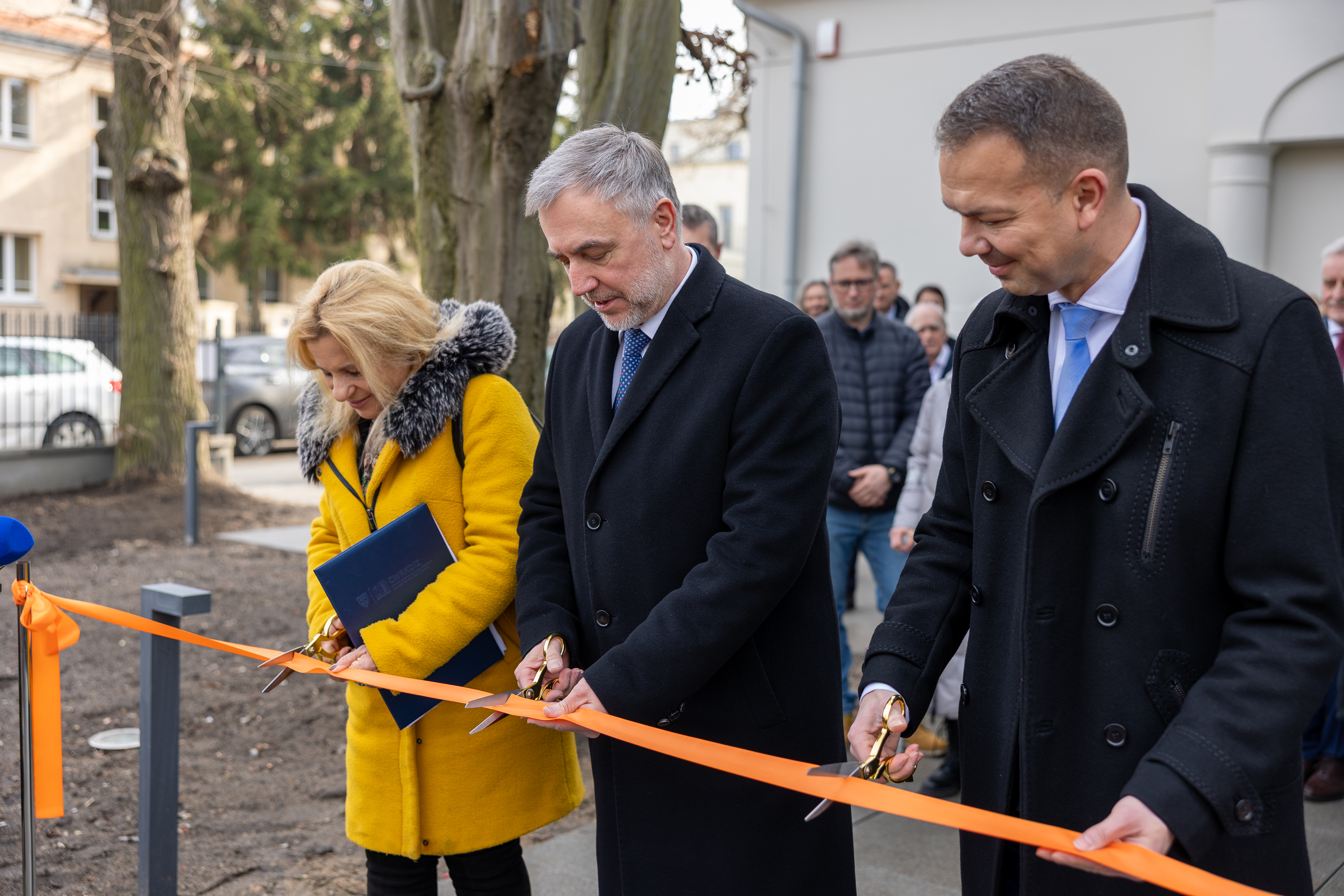 Trzy osoby przecinają wstęgę