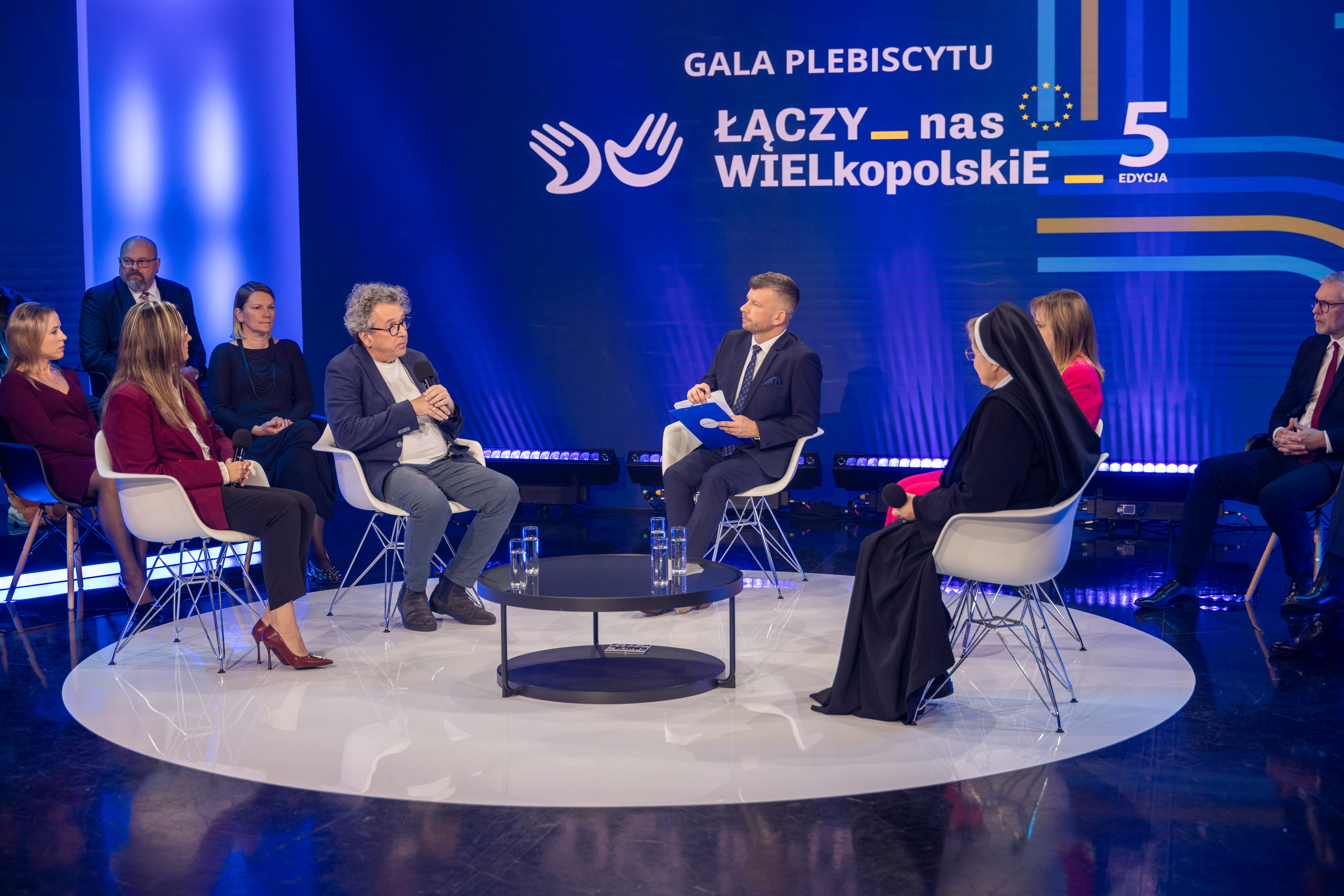 Na zdjęciu pięć osób siedzących na fotelach, którzy ze sobą rozmawiają, w tle napis gala plebiscytu "Łączy nas WIELkopolskiE"