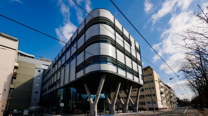 Nowoczesny budynek z falistą elewacją, usytuowany wzdłuż ulicy.