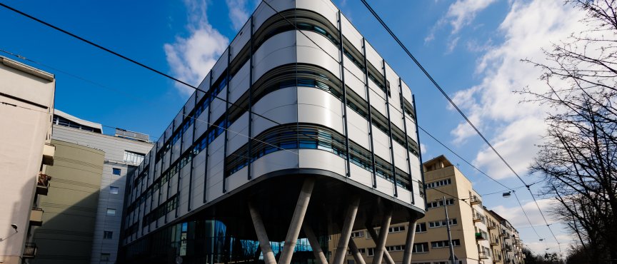 Nowoczesny budynek z falistą elewacją, usytuowany wzdłuż ulicy.