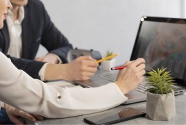 dwie osoby siedzą w biurze przy komputerze