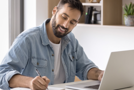 Mężczyzna siedzący przy stole, przed komputerem