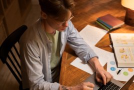 Mężczyzna siedzący przy stole, przed komputerem