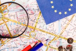 lupa, kredki i chorągiewka z flagą Unii Europejskiej połozone na mapie