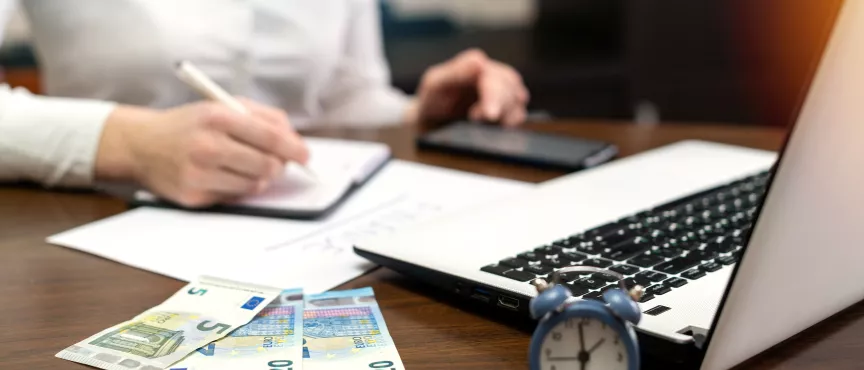 zdjęcie przedstawia kobietę która robi notatki przed komputerem