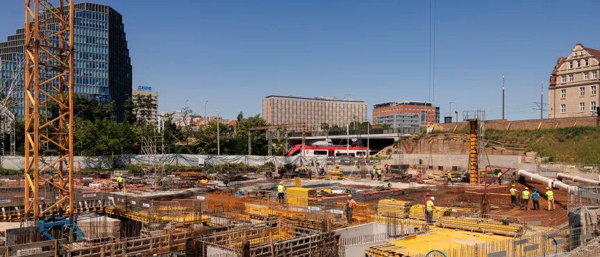 Na zdjęciu widok na teren budowy, w tle wieżowiec i inne budynki w centrum Poznania 