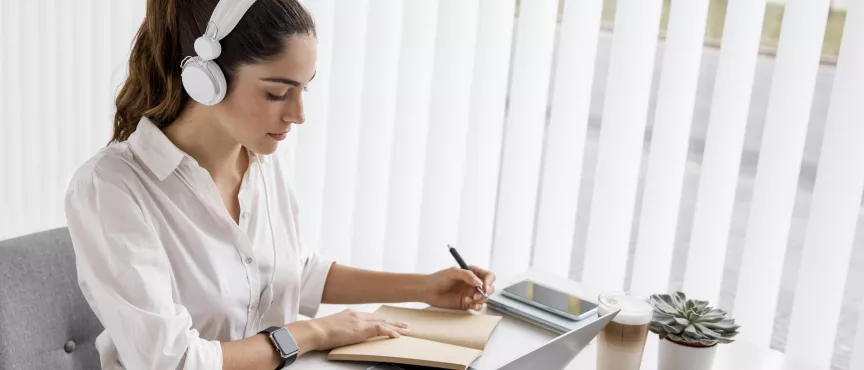 Kobieta z słuchawkami przed laptopem na szkoleniu online