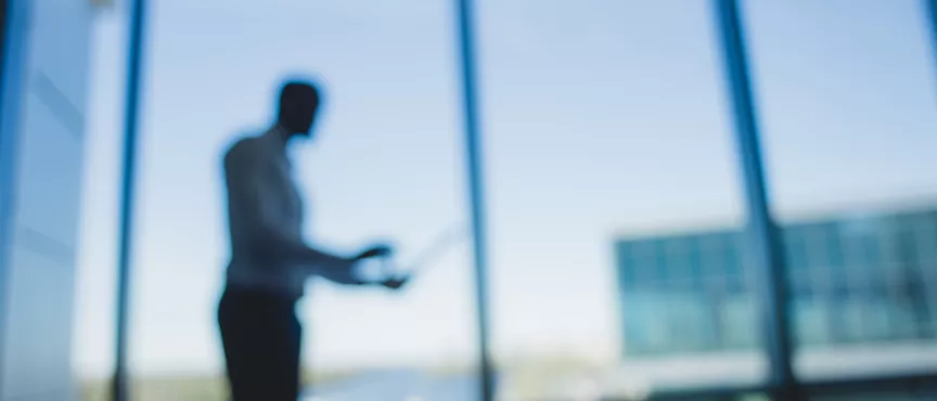 mezczyzna z laptopem na tle okien biurowca