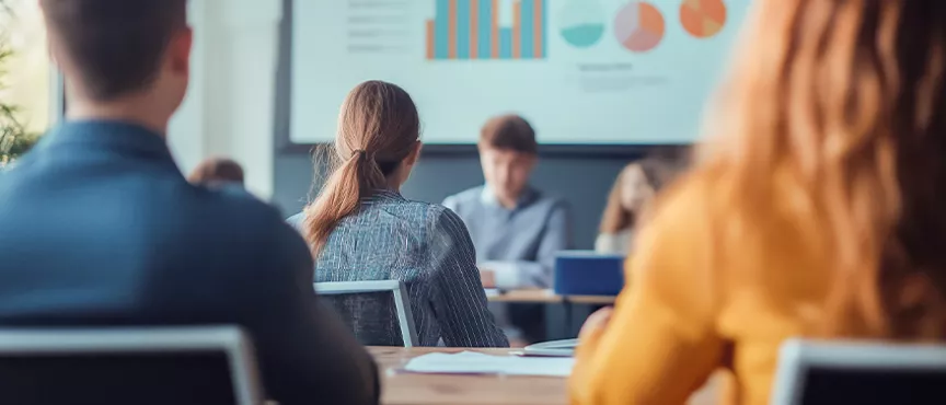 grupa osób na spotkaniu, w tle widać ekran z prezentacją