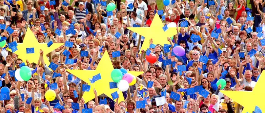 Na zdjęciu tłum ludzi trzymający żółte gwiazdy i niebieskie balony