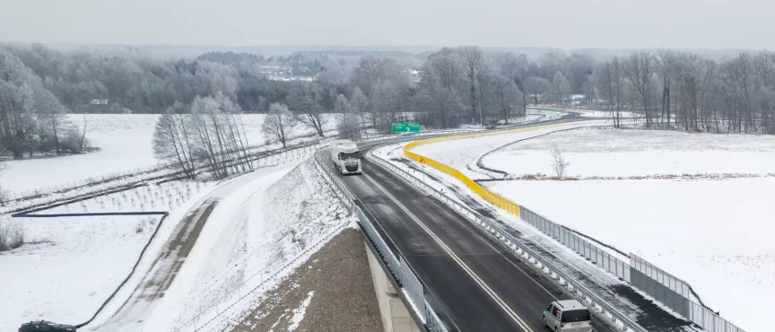 Na zdjęciu widok z lotu ptaka na zaśnieżony wiadukt, a pod nim przejeżdża pociąg