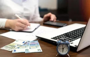 zdjęcie przedstawia kobietę która robi notatki przed komputerem