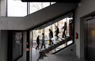 Wygląd wnętrz budynków, z oddali widać schodzące po schodach osoby 