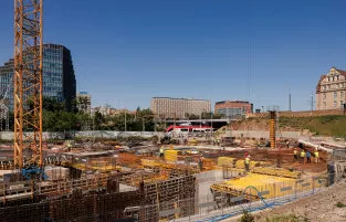 Na zdjęciu widok na teren budowy, w tle wieżowiec i inne budynki w centrum Poznania 