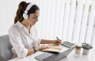 Kobieta z słuchawkami przed laptopem na szkoleniu online