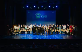 Na zdjęciu kilkanaście osób stojących na scenie, w tle napis "kręcimy lepsze jutro"