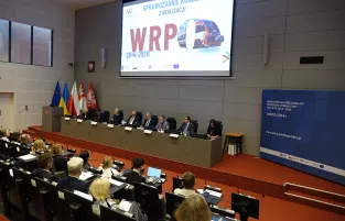 Na zdjęciu widok na stół prezydialny, nad nim napis WRPO