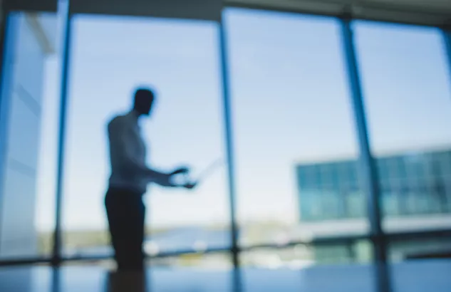 mezczyzna z laptopem na tle okien biurowca