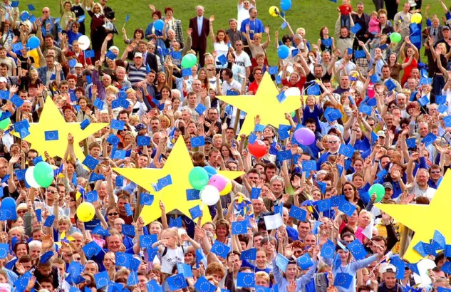 Na zdjęciu tłum ludzi trzymający żółte gwiazdy i niebieskie balony