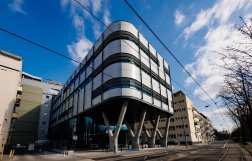 Nowoczesny budynek z falistą elewacją, usytuowany wzdłuż ulicy.