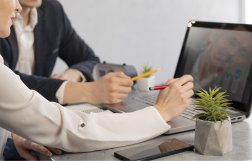 dwie osoby siedzą w biurze przy komputerze