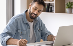 Mężczyzna siedzący przy stole, przed komputerem