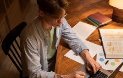 Mężczyzna siedzący przy stole, przed komputerem