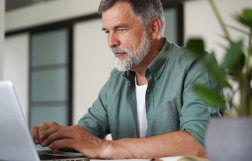 Mężczyzna siedzący przy stole, przed komputerem