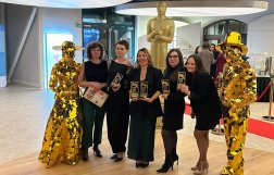 Na zdjęciu pięć uśmiechniętych kobiet, obok stoją posągi 