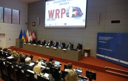 Na zdjęciu widok na stół prezydialny, nad nim napis WRPO