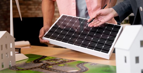 zdjęcie przedstawia panel fotowoltaiczny oraz makiety dwóch domów