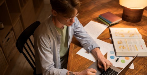 mężczyzna siedzi przy stole i pracuje na komputerze