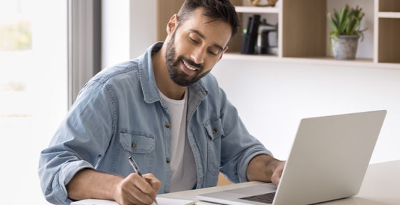 Mężczyzna siedzący przy stole, przed komputerem