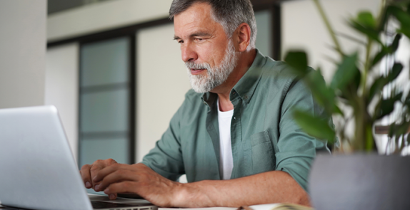 Mężczyzna siedzący przy stole, przed komputerem